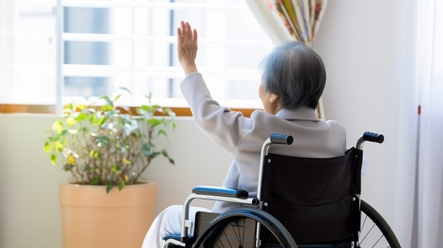 車椅子に乗り手をあげる女性